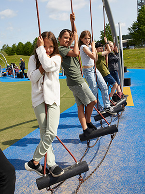 Group of children swing standing on a large rope swing.